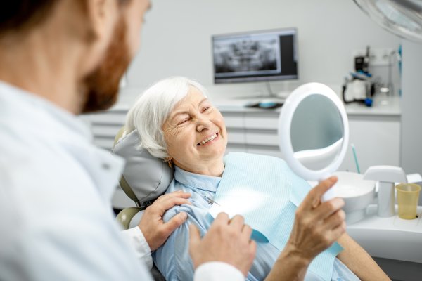 Elderly woman enjoying her smile in the dental office man smiling in dentists chair